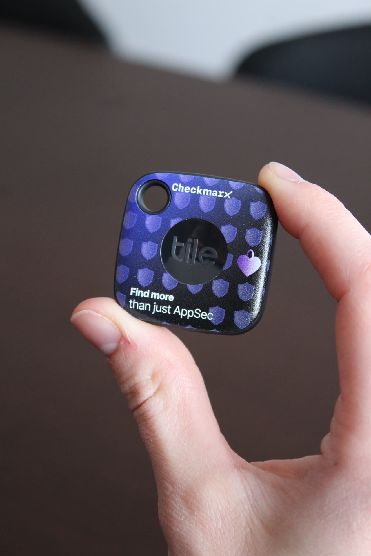 Checkmarx branded Tile bluetooth tracker held in hand
