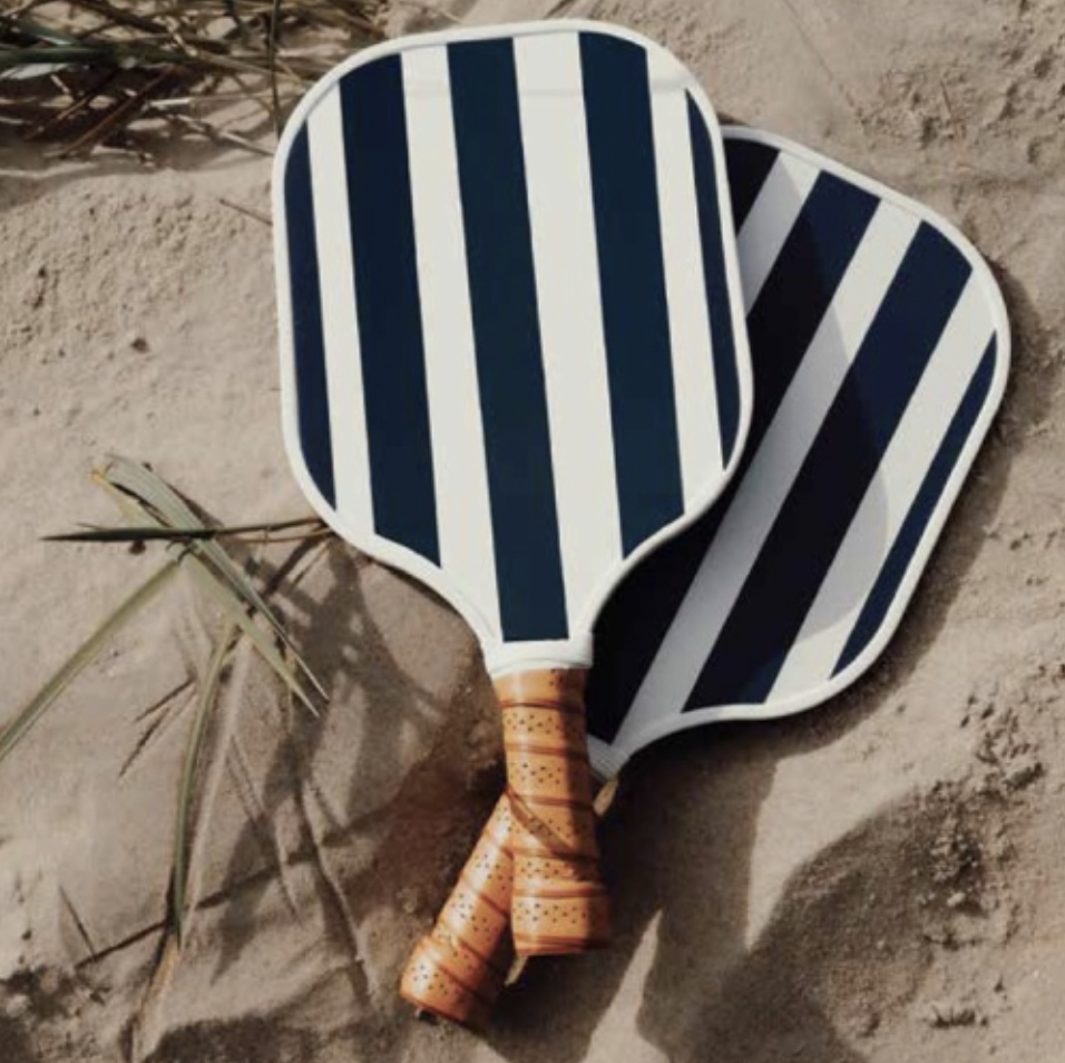 Navy and white striped padel rackets on sand